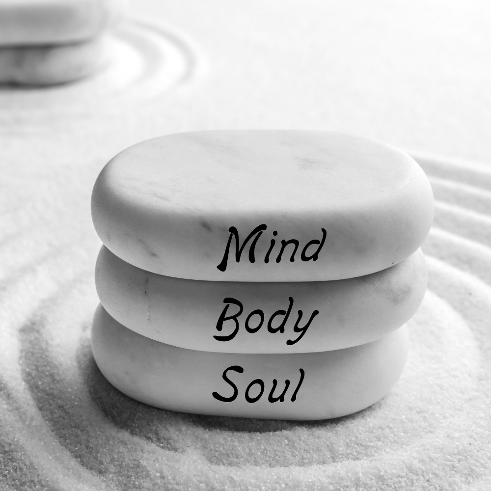 The Essential Blueprint for Holistic Health Three stacked stones with the words "Mind," "Body," and "Soul" engraved on them, set against a backdrop of soft ripples in sand.