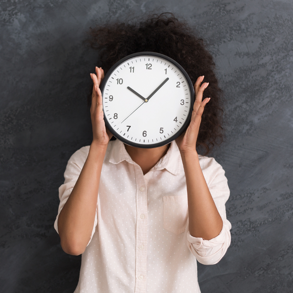 30. Mastering Time Management Strategies for Busy Women Woman holding a large clock over her face, symbolising time management challenges.