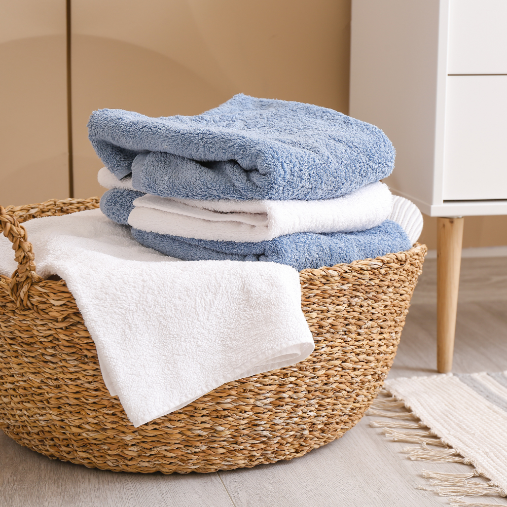 Stack of neatly folded blue and white towels in a woven basket, symbolising small everyday wins like tidying up or finishing chores.